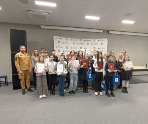 Uczestnicy gminnych eliminacji turnieju wiedzy pożarniczej stoją w grupie z dyplomami i nagrodami. Towarzyszą im organizatorzy oraz przedstawiciel straży pożarnej.