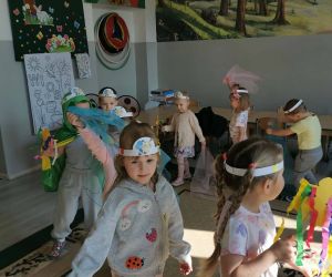 Dzieci z oddziału przedszkolnego uczestniczą w zabawach ruchowych w sali, trzymając kolorowe chustki i wstążki