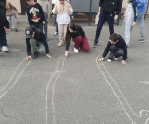 Uczniowie grają w kapsle na placu szkolnym