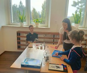 Uczennica klasy ósmej pomaga młodszej dziewczynce wykonać eksperyment fizyczny