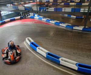 Gokart poruszający się po torze wewnętrznym, widoczne bandy zabezpieczające trasę.