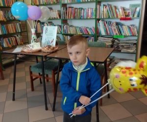Zdjęcie przestawia chłopca trzymającego balony.