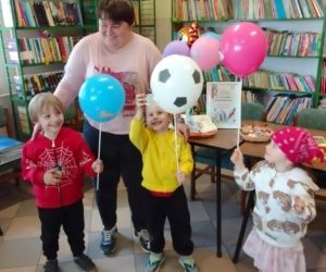 Na zdjęciu widoczna jest kobieta z trójką dzieci, które trzymają balony.