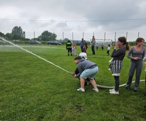Pokaz strażacki – dzieci próbują swoich sił w obsłudze strażackiego węża pod nadzorem strażaków.