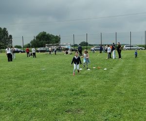 Dzieci uczestniczą w konkurencji sportowej na szkolnym boisku podczas Dnia Rodziny.
