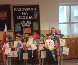 Uczniowie stoją z wychowawczynią, trzymają w ręku rożek ze słodyczami oraz dyplomy