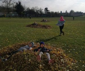 Dzieci skaczą w stos liści