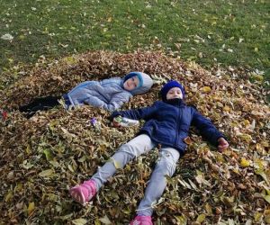 Dwoje uczniów leży na stosie liści