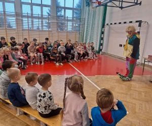 Dzieci siedzą i oglądają występ klowna