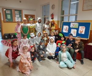 Dzieci z nauczycielką przebrane za postaci z bajek stoją na korytarzu szkolnym