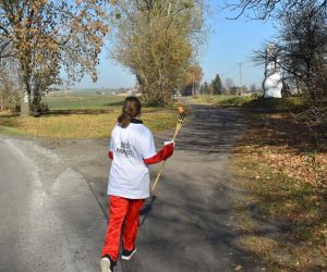 Droga. Jedna osoba biegnie z pochodnią. W oddali kapliczka