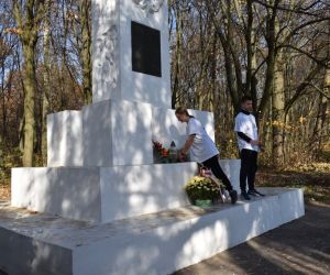 Pomnik przy lesie. Dwie osoby. Składanie wiązanki