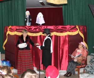 Kukiełki w przedstawieniu teatrzyku kukiełkowym. Osoby odgrywają scenkę teatralną przed parawanem.