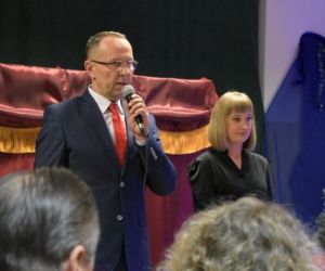 Dwie osoby przemawiają do mikrofonu wewnątrz budynku.