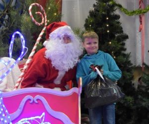 Dziecko odbiera paczkę od Mikołaja.