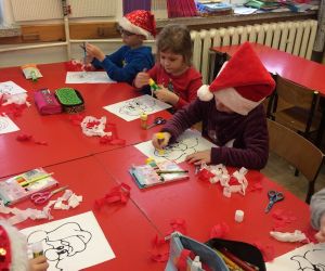 Dzieci wyklejają bibułą portret Św. Mikołaja.