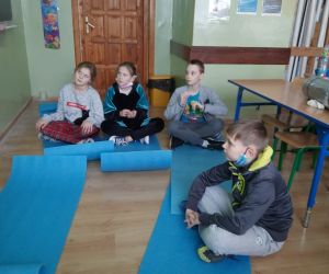 Uczniowie  siedzą na matach i słuchają baśni