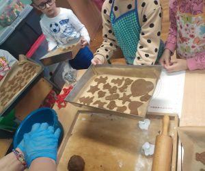 dzieci ukłądają pierniczki na blaszce