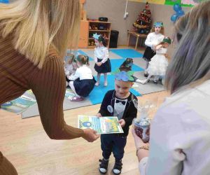 Dyrektor szkoły i jedna z wychowawczyń wręczają chłopcu pamiątkowy dyplom i drobny upominek