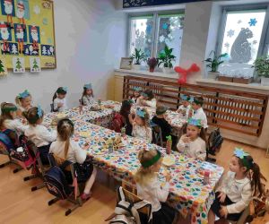 Grupa przedszkolaków spożywa poczęstunek przy stole