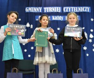 Dzieci wewnątrz budynku prezentują nagrody oraz dyplom.