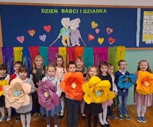 dzieci stoją z kwiatkami podczas występu