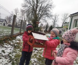 dziewczynka i chłopiec dosypują karmę dla ptaków