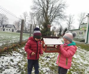 dziewczynka i chłopiec dokarmiają ptaki