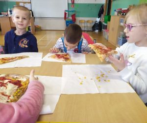 dzieci spożywają pizzę
