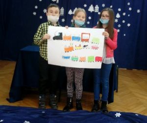 Chłopiec i dwie dziewczynki stoją na scenie i prezentują swoją pracę konkursową