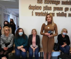 Dyrektor szkoły przemawia do zgromadzonych uczniów, stojąc. Za nią nauczycielki siedzące na ławce