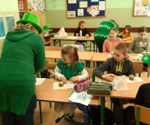 Uczniowie ozdabiają zielone babeczki a panie nauczycielki pomagają im