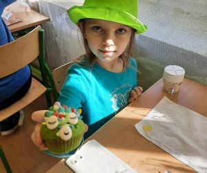 Uczennica trzyma udekorowaną przez siebie babeczkę