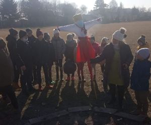 Uczniowie stoją w kole a nauczycielka podpala Marzannę