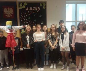 Uczniowie stoją na korytarzu z Marzanną a  obok stoi dziewczynka i trzyma klucz do współrządzenia szkołą