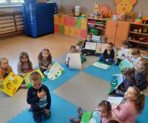 Przedszkolaki siedzą w kręgu i prezentują swoje prace plastyczne o tematyce wiosennej
