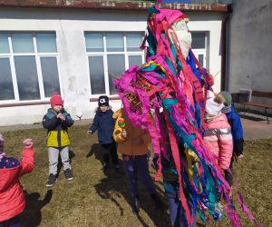 Dzieci śpiewają piosenki i trzymają Marzannę