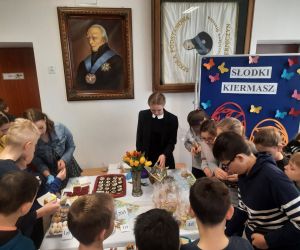 Uczniowie zgromadzeni wokół stołu z ciastami