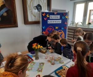 Uczniowie zgromadzeni wokół stołu z ciastami dokonują zakupu