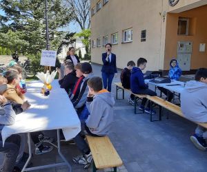 Panie z biblioteki witają uczniów na warsztatach, uczniowie siedzą przy stolikach ustawionych na placu przed HDK.