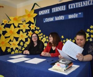 Jury siedzi przy stoliku wewnątrz budynku.