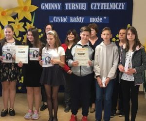 Chłopcy i dziewczęta - uczestnicy turnieju czytelniczego  na tle tablicy dekoracyjnej