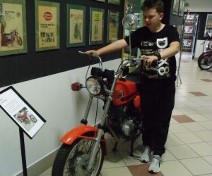 Uczeń trzyma kierownicę zabytkowego motoru w Muzeum Strefa Historii w Świdniku