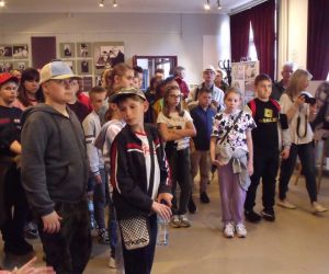 Uczniowie w bibliotece w Świdniku wraz z opiekunami i przewodnikiem oglądają wystawę poświęconą pisarce Annie Kamieńskiej