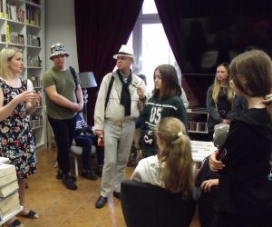 Uczniowie wraz z przewodnikiem w bibliotece w Świdniku, słuchają opowieści bibliotekarki o zbiorach bibliotecznych