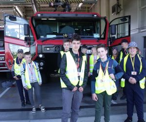 Uczniowie przed budynkiem straży pożarnej, w którym znajduje się nowoczesny sprzęt do gaszenia pożarów na wypadek awarii statków powietrznych