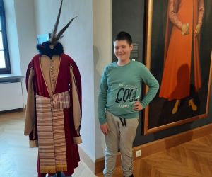 Uczeń stoi obok stroju hetmana a obok na ścianie wisi obraz z hetmanem