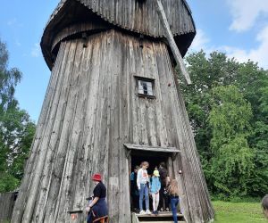 Uczniowie stoją przy wejściu do drewnianego młyna tzw. holenderskiego, który znajduje się w skansenie