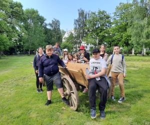 Uczniowie stoją  przy drewnianym wozie drabiniastym