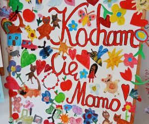 Tablica dekoracyjna z obrazkami malowanymi przez dzieci i napisem
Kocham Cię Mamo!